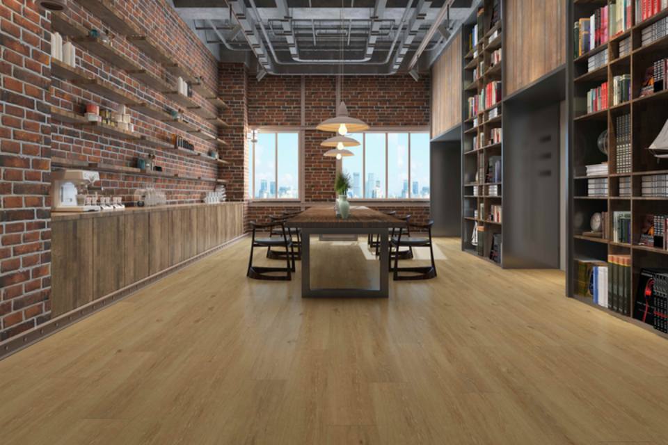 warm toned wood look flooring in library with red brikc walls and long table with chairs.